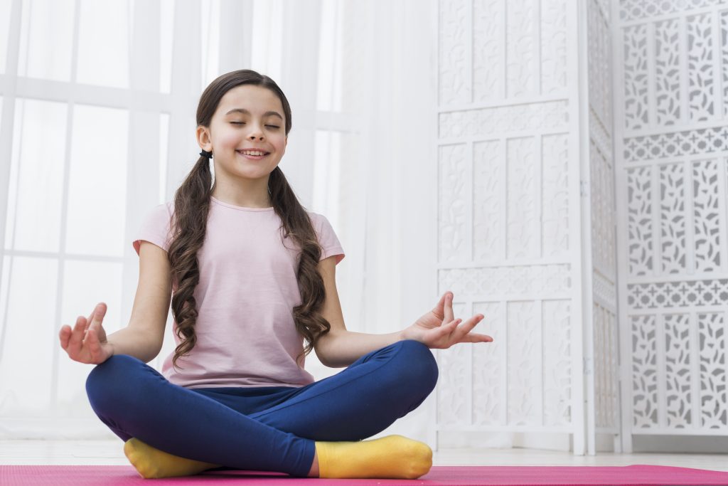 Niña practicando yoga para aprender a regular sus emociones.